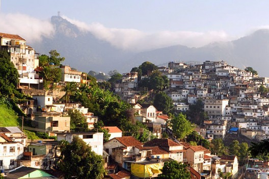 In the background you can see the Santa Teresa Favela in Rio de Janeiro, in contrast to the wealthy neighborhood in the foreground. Image via Wikimedia Commons User chensiyuan