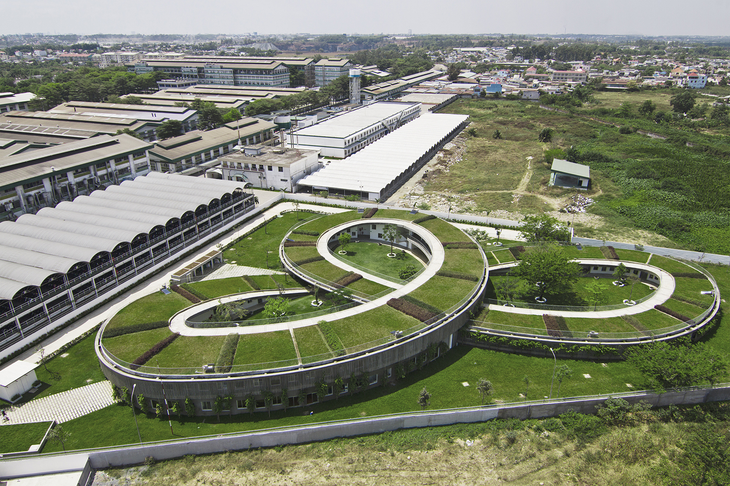54624917e58ecee2b400003d_farming-kindergarten-vo-trong-nghia-architects_03_aerial_view_from_ne_with_the_shoe_factory_behind_the_building.jpg