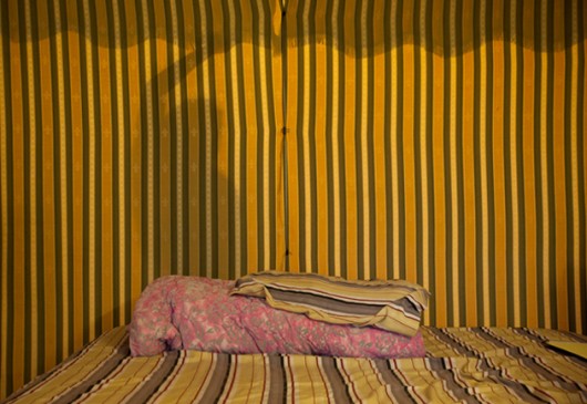 SITU documentation of a shared apartment in Flushing, Queens, where a curtain divides a living room from a sleeping area. Image © Jeyhoun Allebaugh