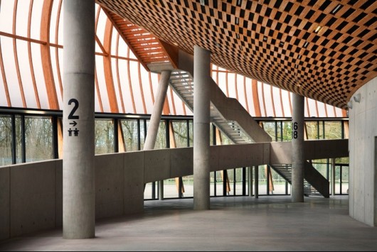 The mass of the auditorium is distributed onto thin columns that penetrate the foyer. Image Courtesy of Bernard Tschumi Architects